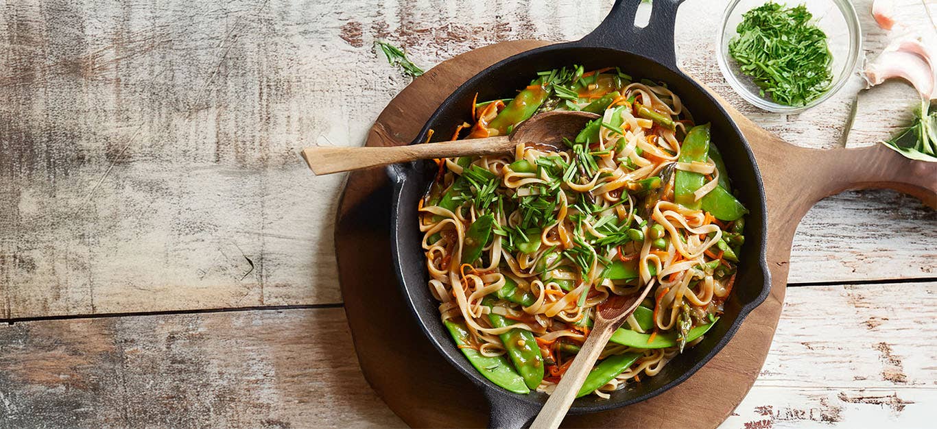 Stir-Fried Noodles with Veggies in a case-iron pan, with a small bowl of freshly cut chives to the side