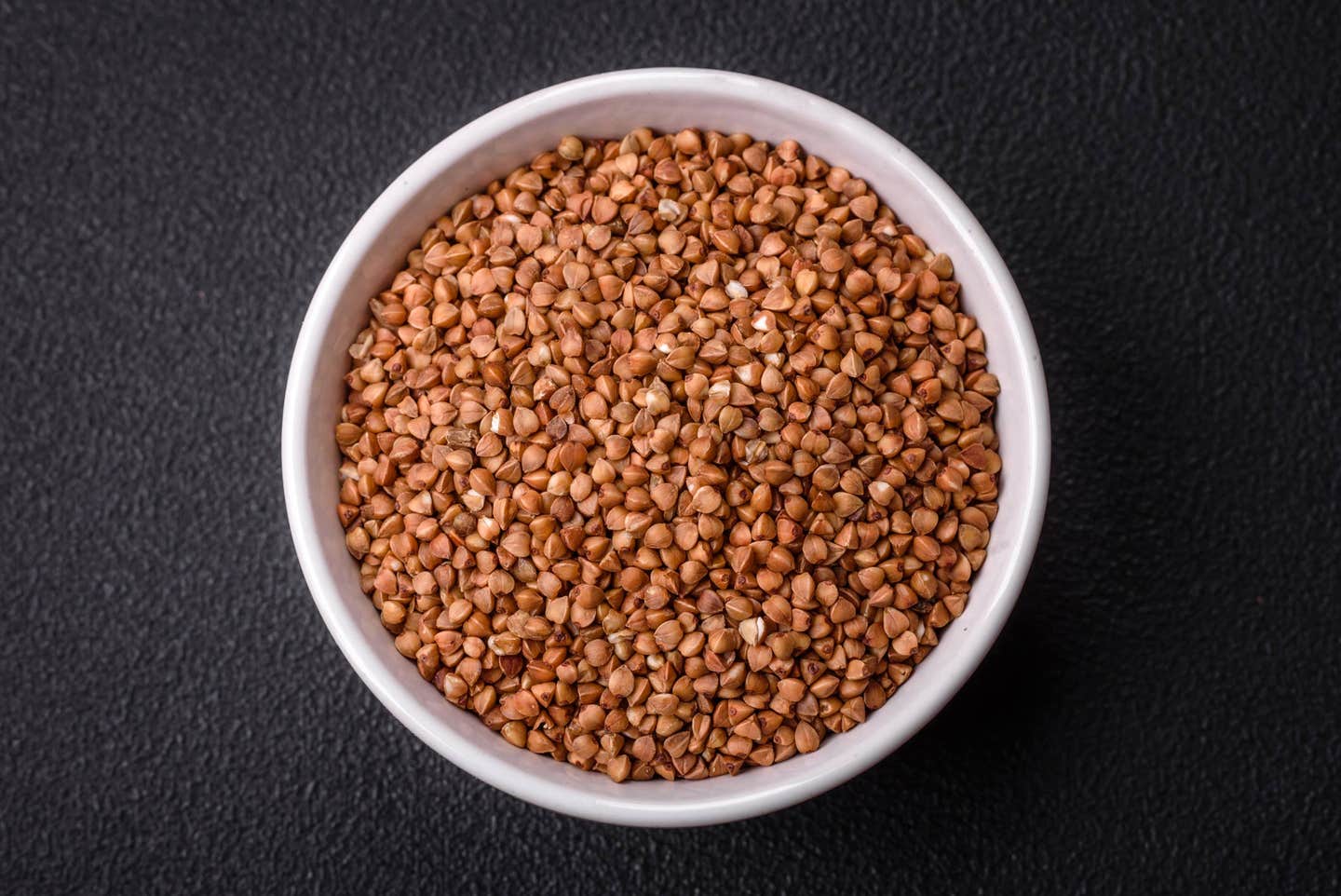 Buckwheat graots in a bowl on a solid gray background