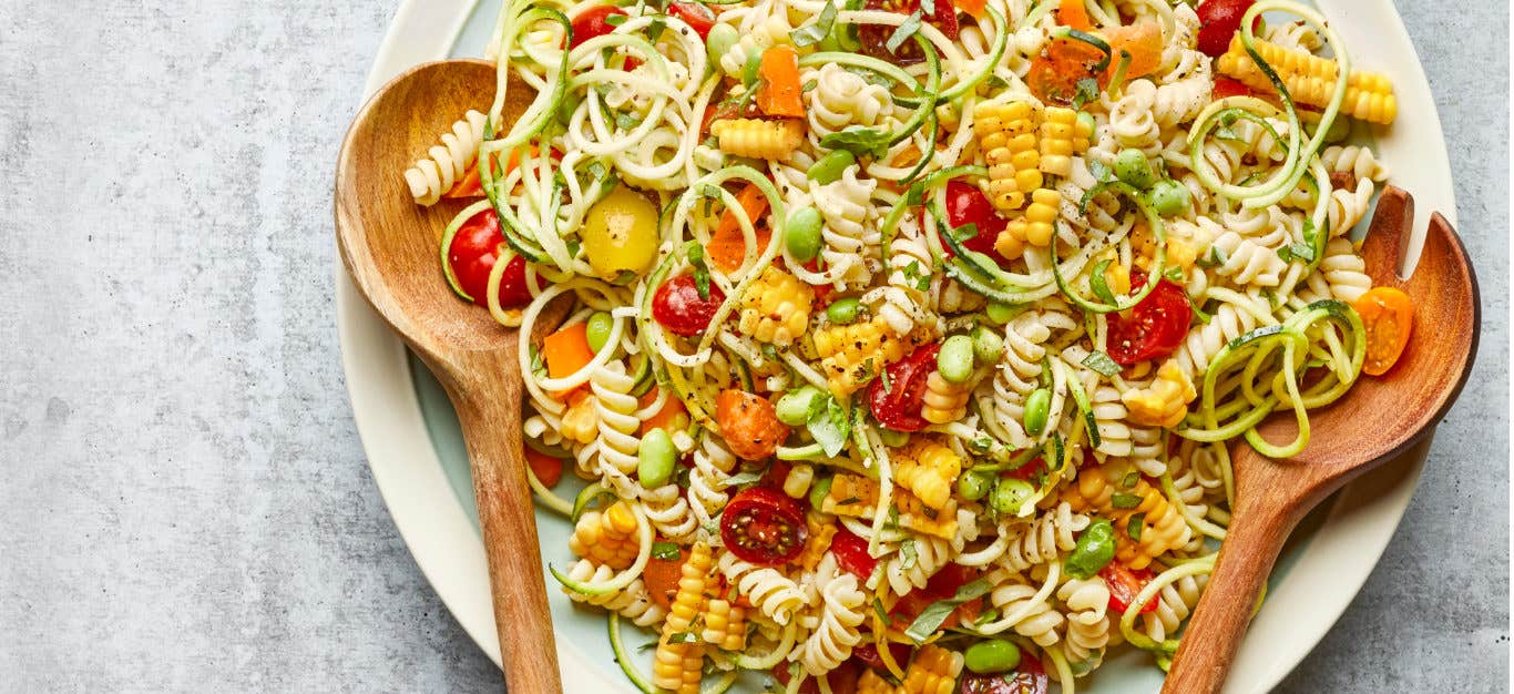 Confetti Corn and Pasta Bowl on a white platter with wooden serving spoons