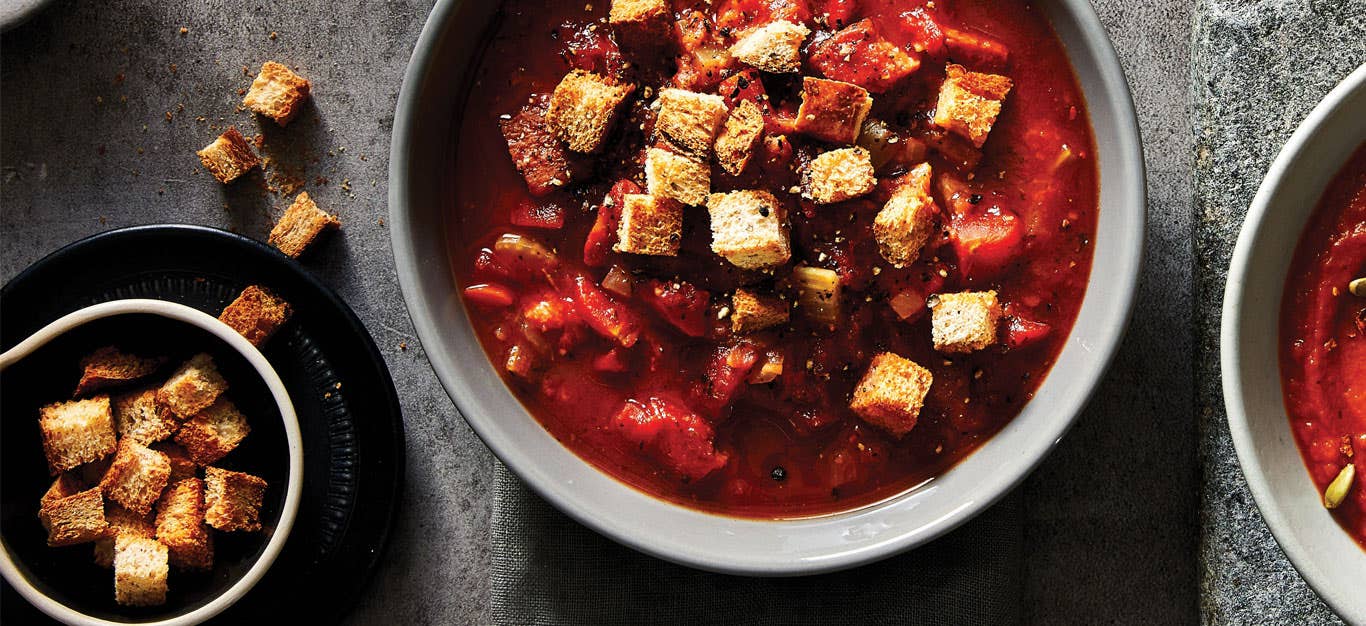 Spicy Tomato Soup with Whole Wheat Croutons in grey ceramic bowls against a slate countertop