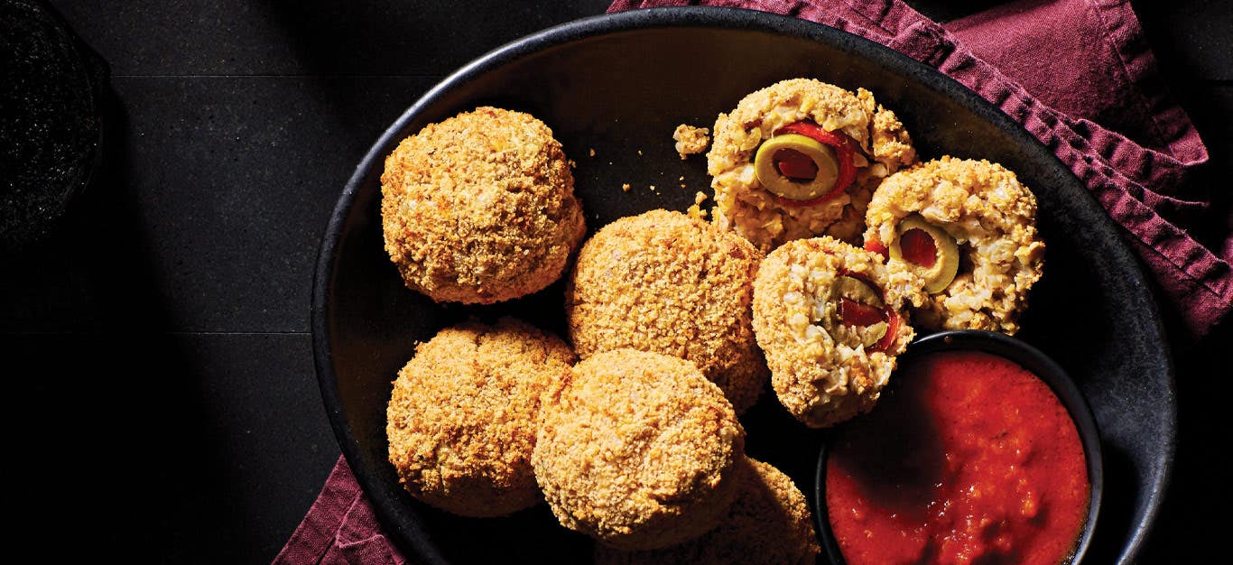 Air-Fried Arancini in a black ceramic bowl served with a side of marinara sauce