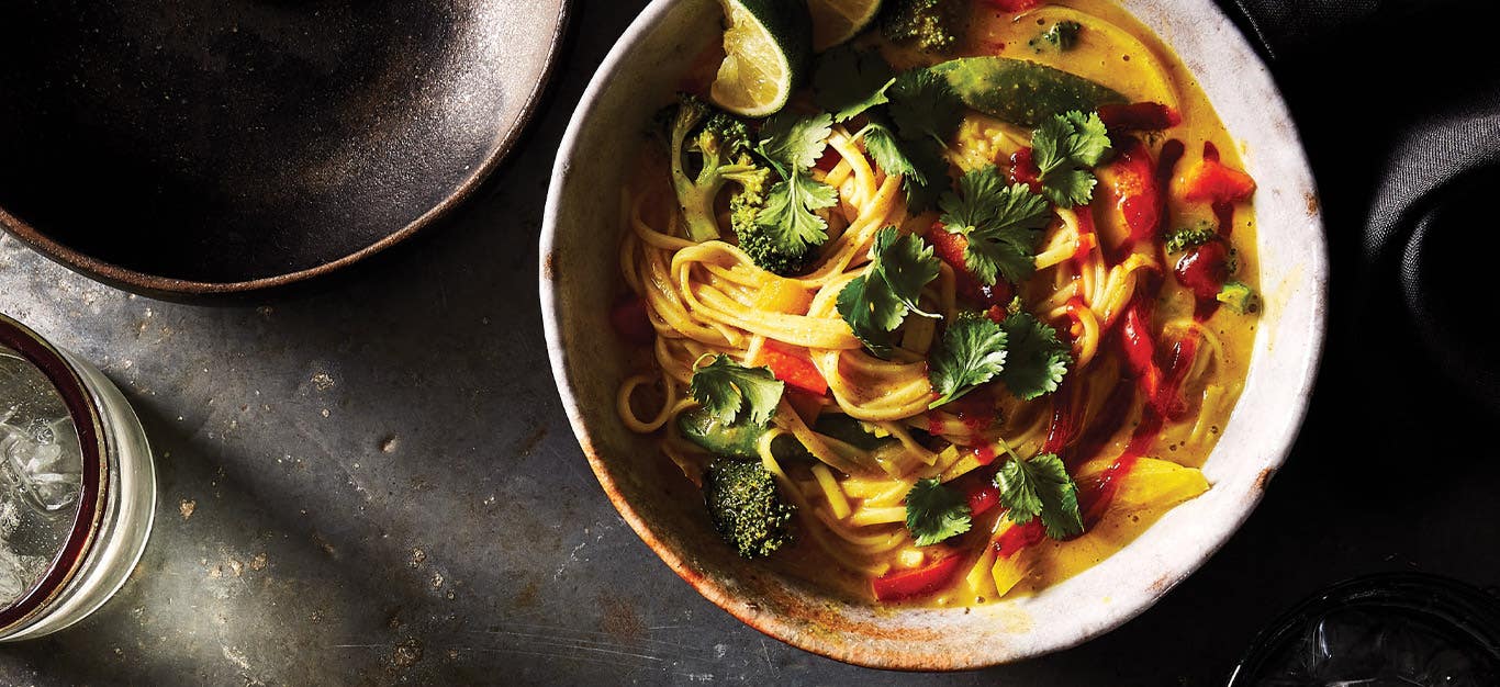 Khow Suey (Burmese Curry Noodle Soup) in a white ceramic bowl against dark gray background