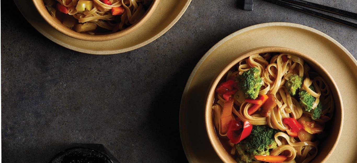 Brown Rice Noodle Bowls with Ginger-Garlic Sauce in light brown ceramic bowls against a dark gray background