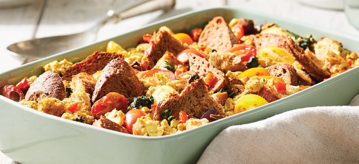 Scrambled Tofu Casserole with Mushrooms and Spinach in a light green ceramic casserole dish