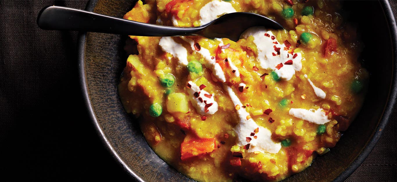 Khichdi (Spiced Lentil and Rice Porridge) in a gray ceramic bowl with a black metal spoon