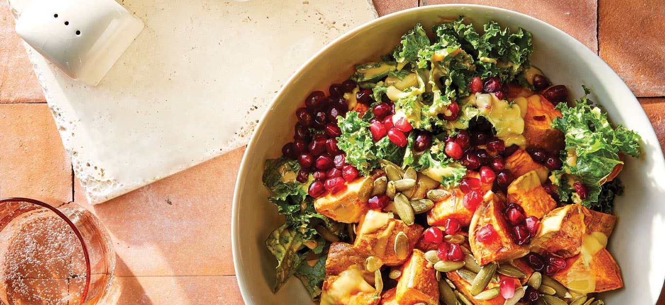 Cornucopia Kale Salad in a white ceramic bowl against a pink tile background