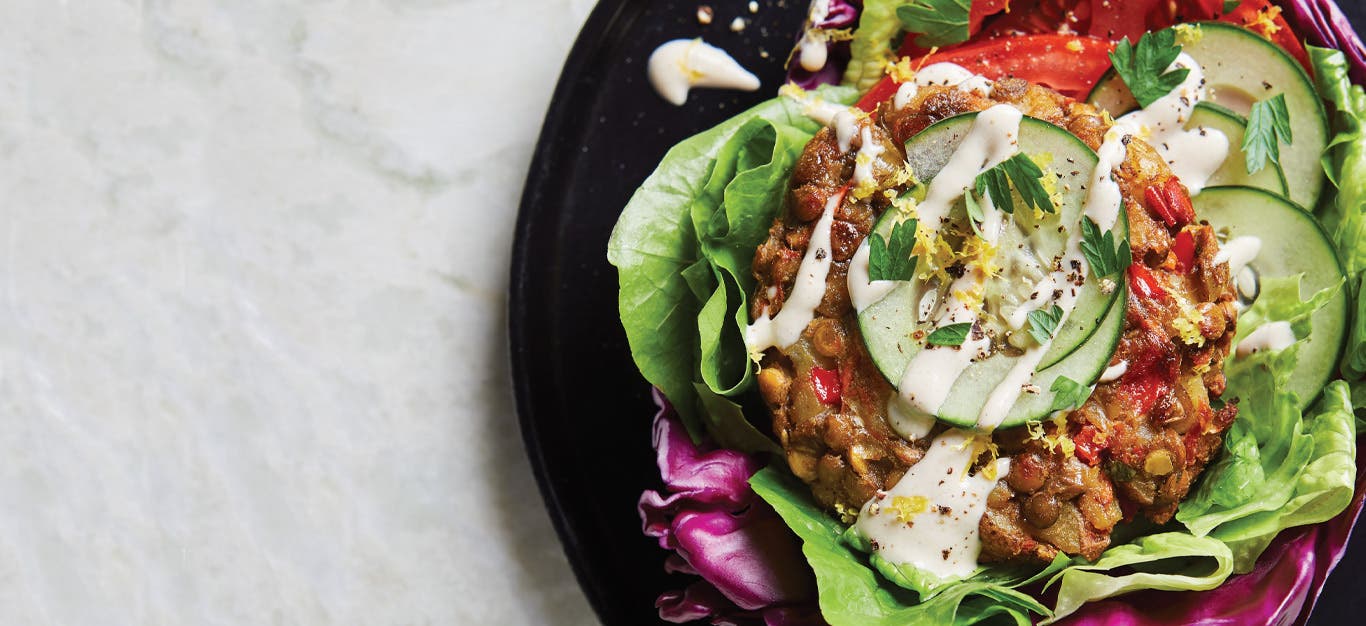 Lebanese Lentil Burgers in Cabbage Pockets on a black plate against a white marble background