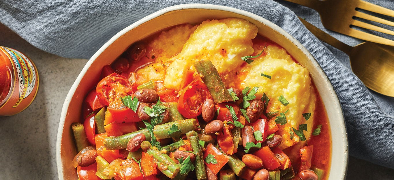 Spicy Cajun Hash on Grits in a white ceramic bowl on top of a blue cloth napkin