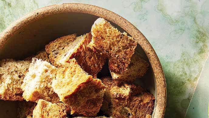 A rustic brown bowl of crusty croutons