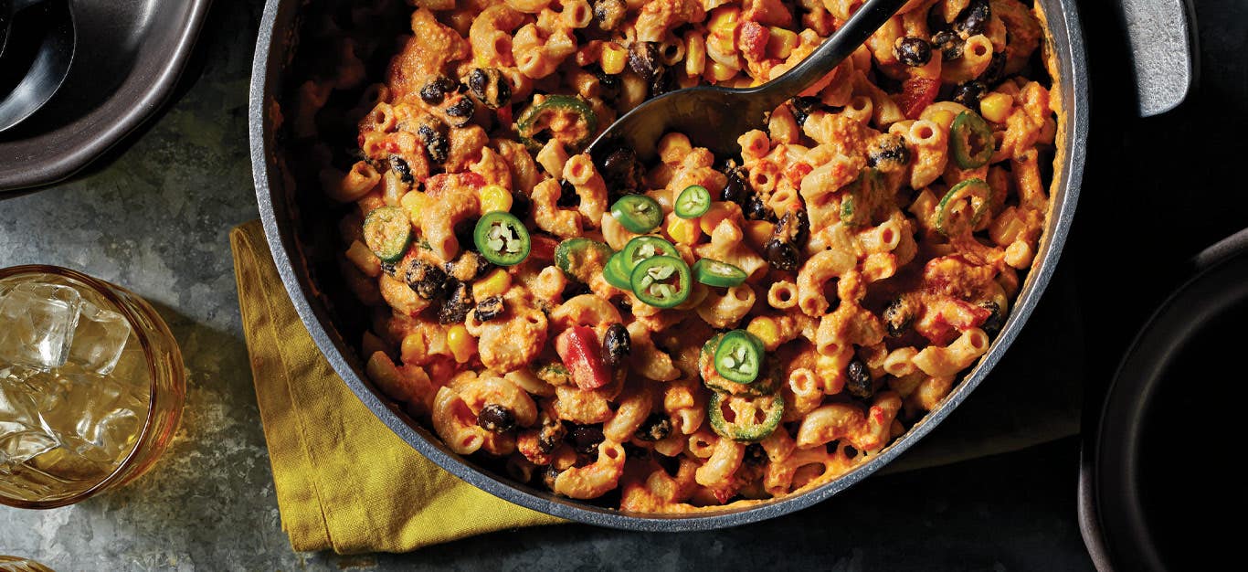 Vegan Chili Mac and Cheese in a large metal pot with a metal spoon stuck in the middle