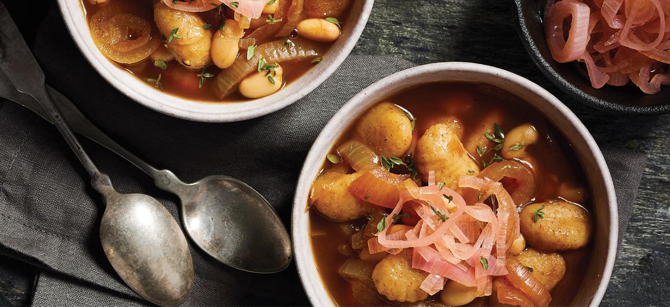 French Onion Gnocchi Soup in a white bowls against a dark gray background