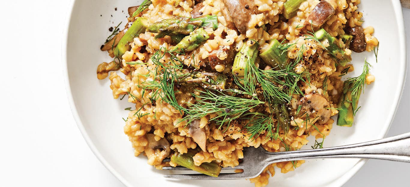 Wild Mushroom and Asparagus Risotto in a white ceramic bowl with a metal fork