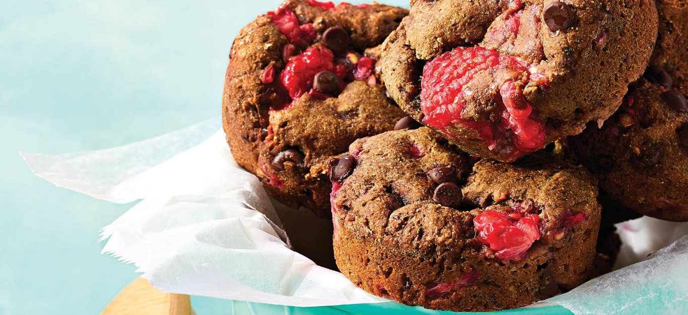 Closeup of three Chocolate Raspberry Brownie Bites on a pale blue background in a bowl with a white napkin