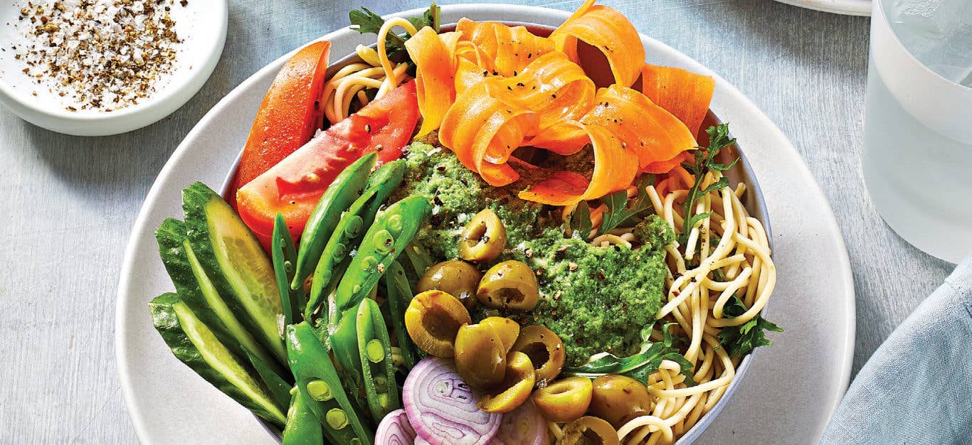 Chilled Noodle Bowls with Mixed Veggies and Minted Pea Dressing in a shallow white bowl sitting on a white plate on a pale grey tablecloth