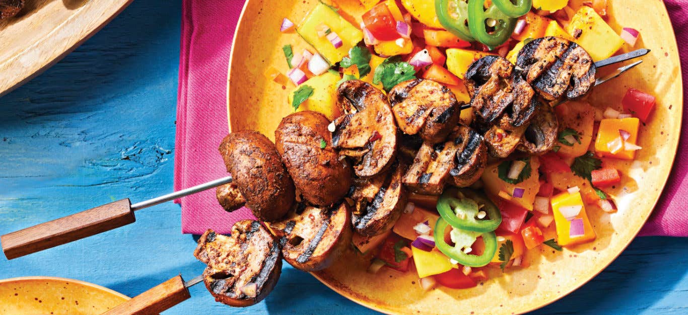 Spicy Jerk Mushroom Kabobs with Mango Salsa on a yellow plate on a bright pink napkin on a blue table