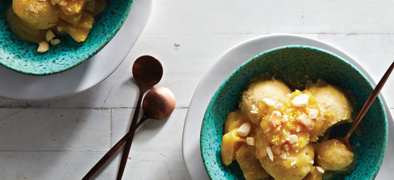 Two bowls of Dairy-Free Jackfruit Ice Cream in a specked green bowl nested on a white plate on a white countertop next to two small copper spoon