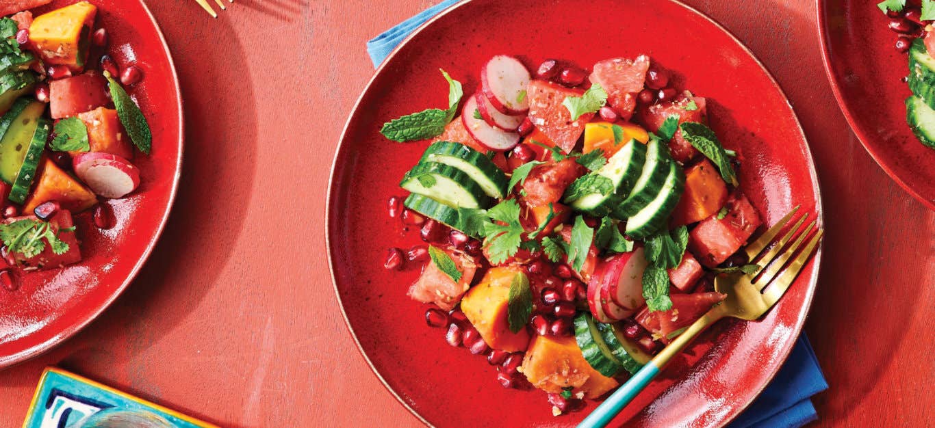 Tropical Fruit Salad with Ginger-Lime Dressing on a red plate sitting on a dusky pink background