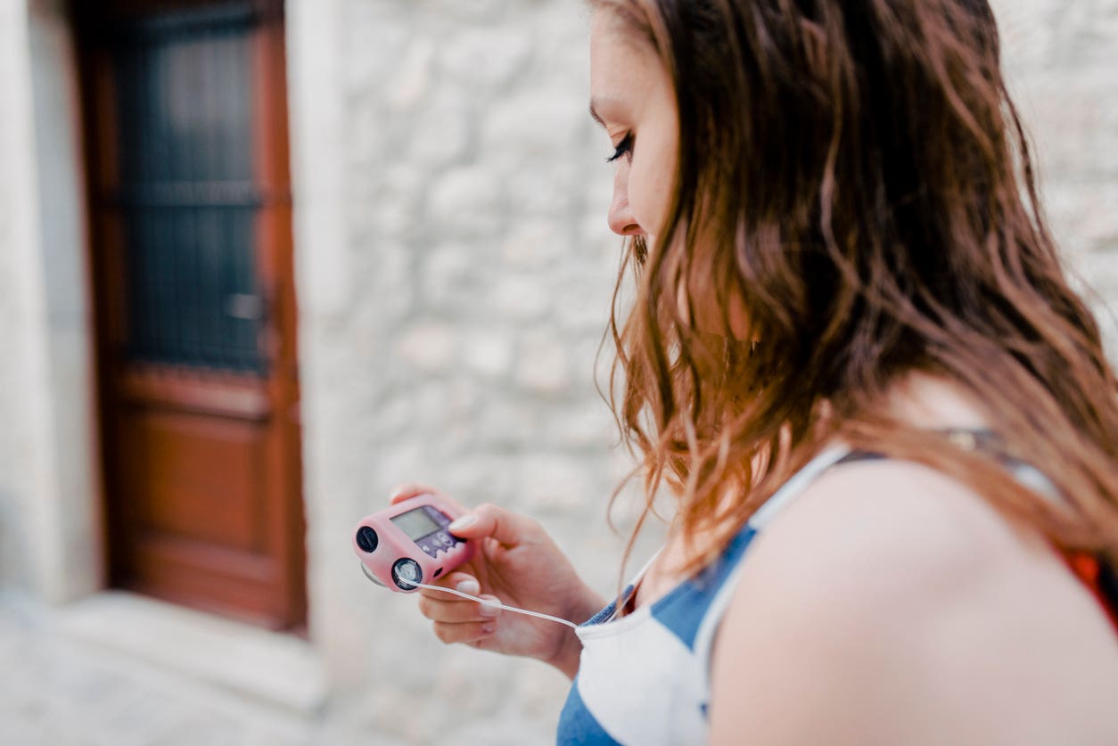 Young woman with Type 1 diabetes reading her insulin pump