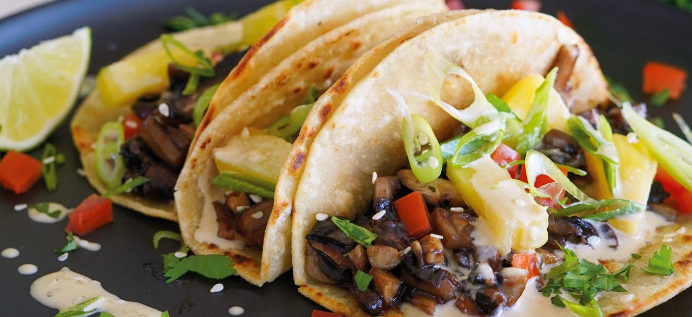 Three of Kiki Nelson’s Hawaiian Street Cart Tacos on a dark plate with a wedge of lime