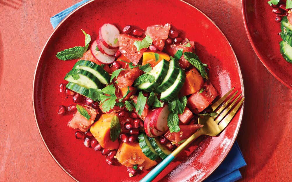 Tropical Fruit Salad with Ginger-Lime Dressing on a red plate sitting on a dusky pink background