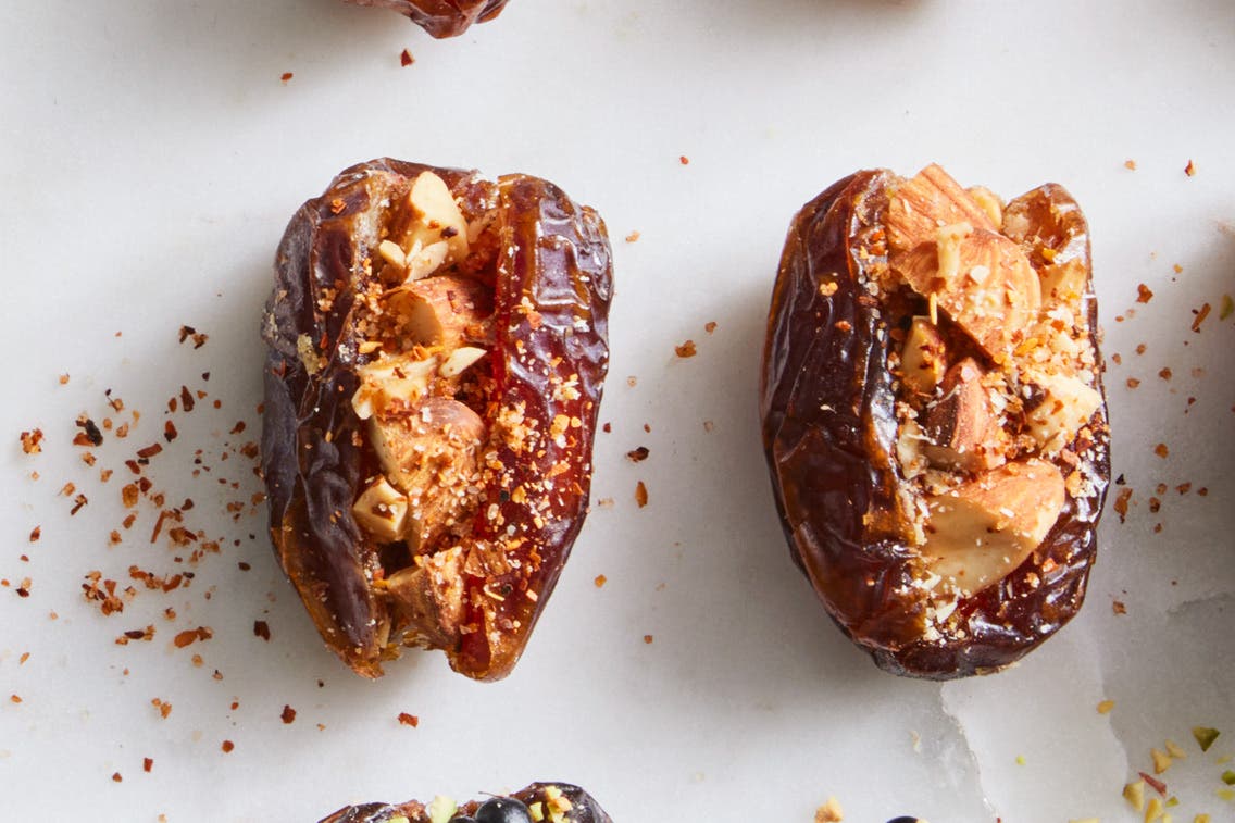 Two Medjool dates cut open and stuffed with almonds that have been tossed in lime juice and chile-lime seasoning