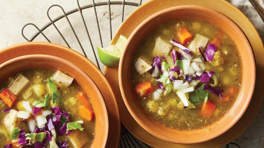 Jackfruit Pozole Verde in orange terracotta bowls with lime wedges on the side