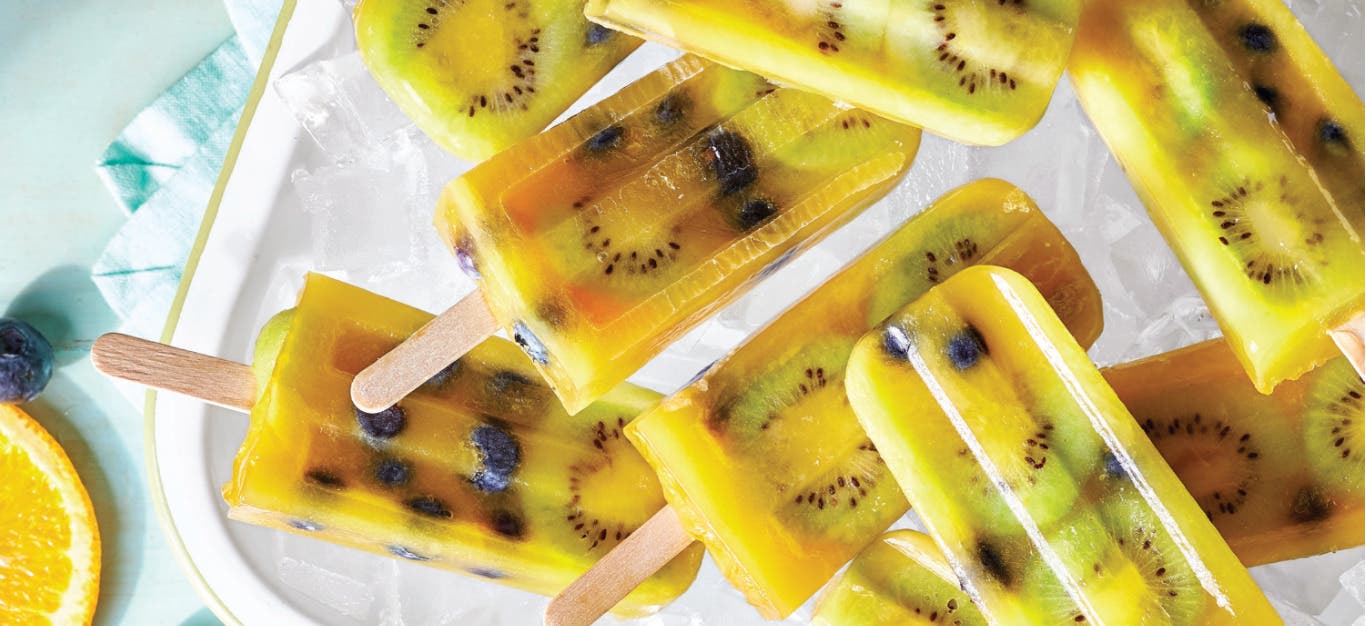 Half a dozen Kiwi-Blueberry Orange Ice Pops on a white platter