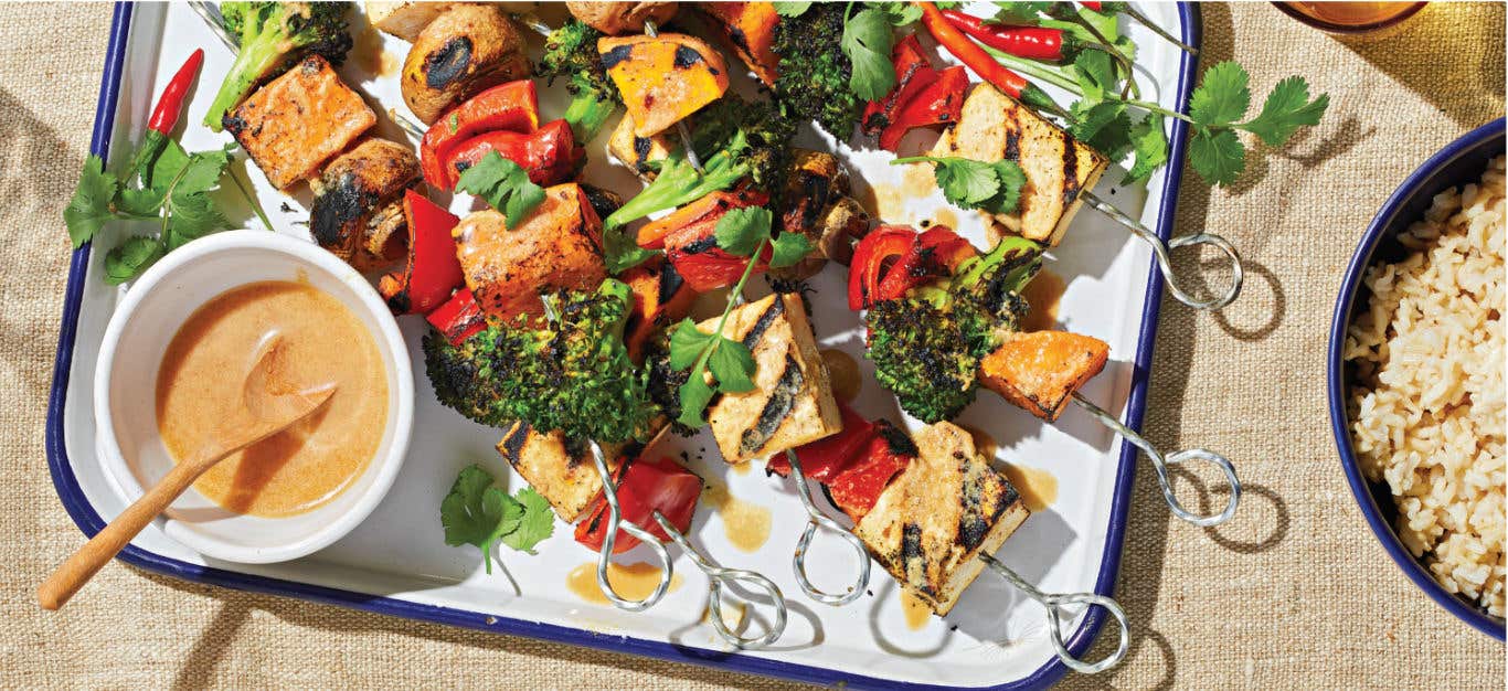 Grilled Veggie and Tofu Skewers on a white platter with a small bowl of Peanut Sauce to the side