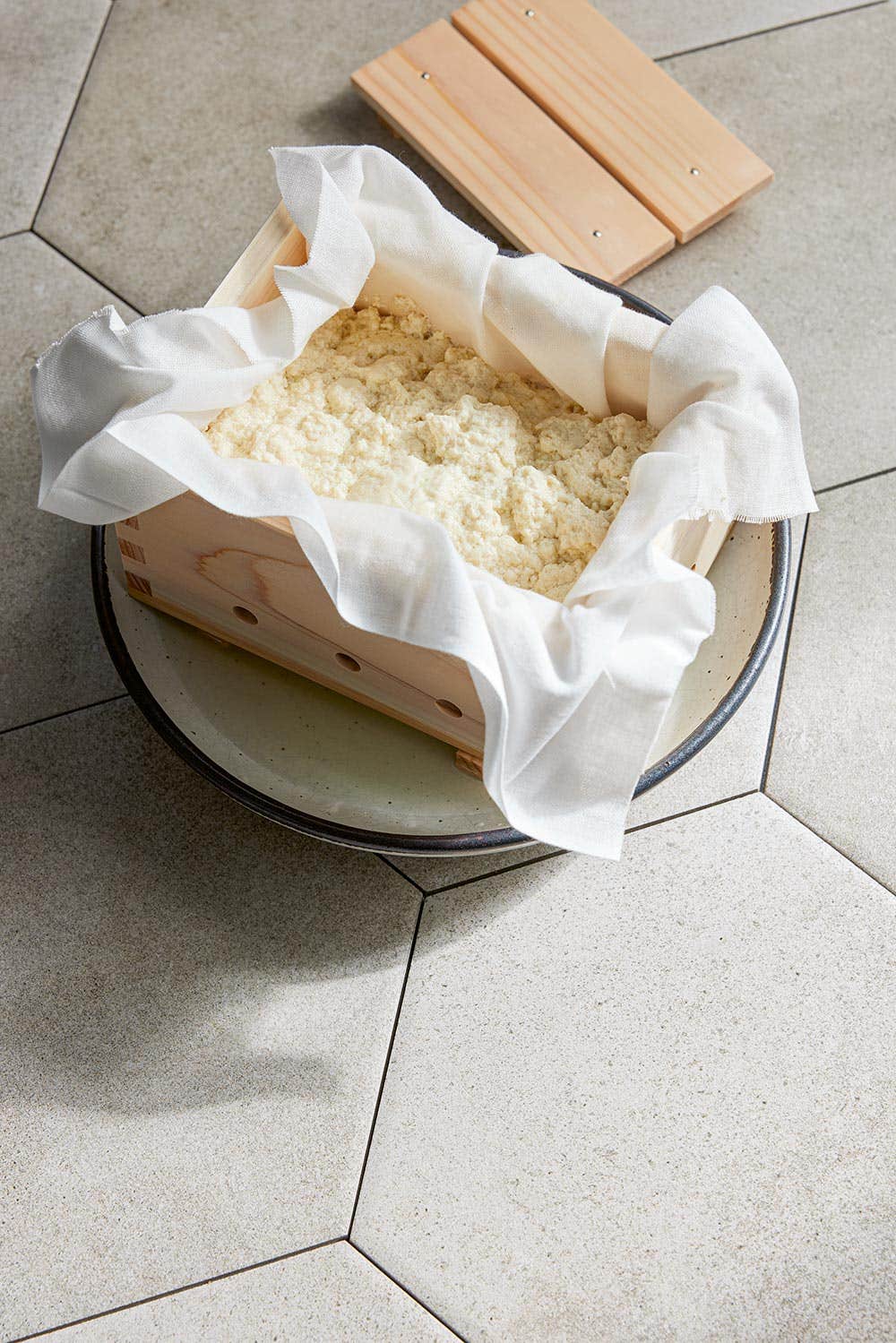 homemade tofu in a cheesecloth-lined wooden box