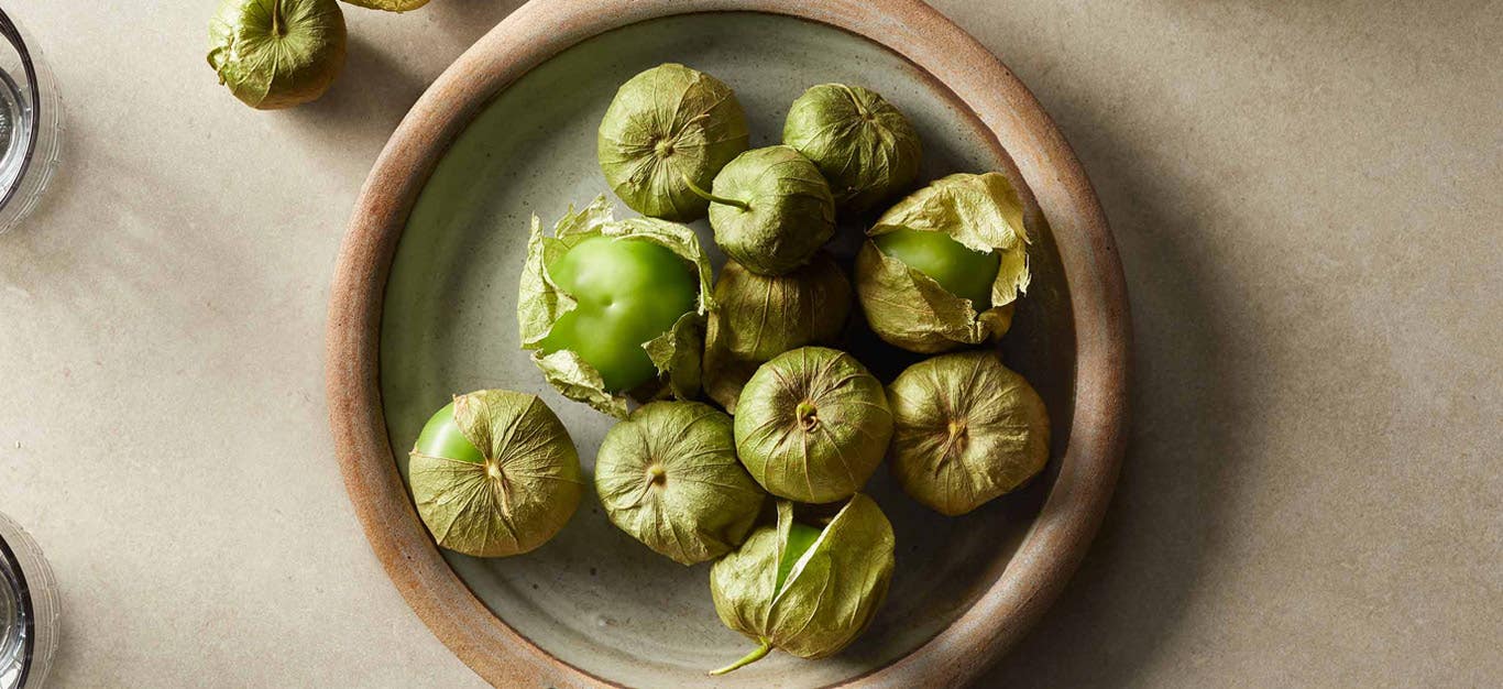 whole tomatillos in their husks in a ceramic bowl in natural lighting