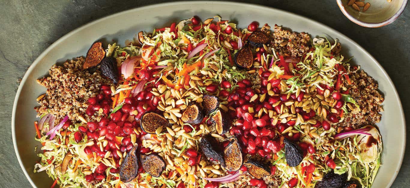 Crunchy Brussels Sprout Slaw with Figs, Pomegranate and Quinoa in a large pale green ceramic platter