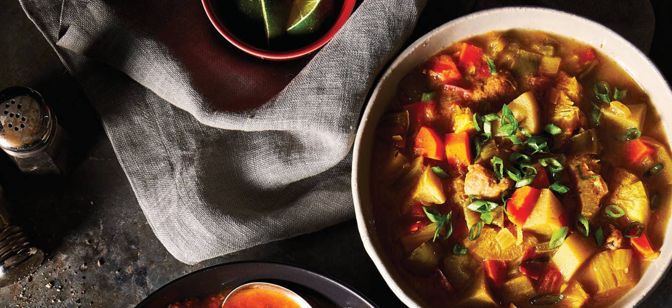 Jamaican Vegetable Stew with Mini Dumplings on a black table next to a grey linen napkin