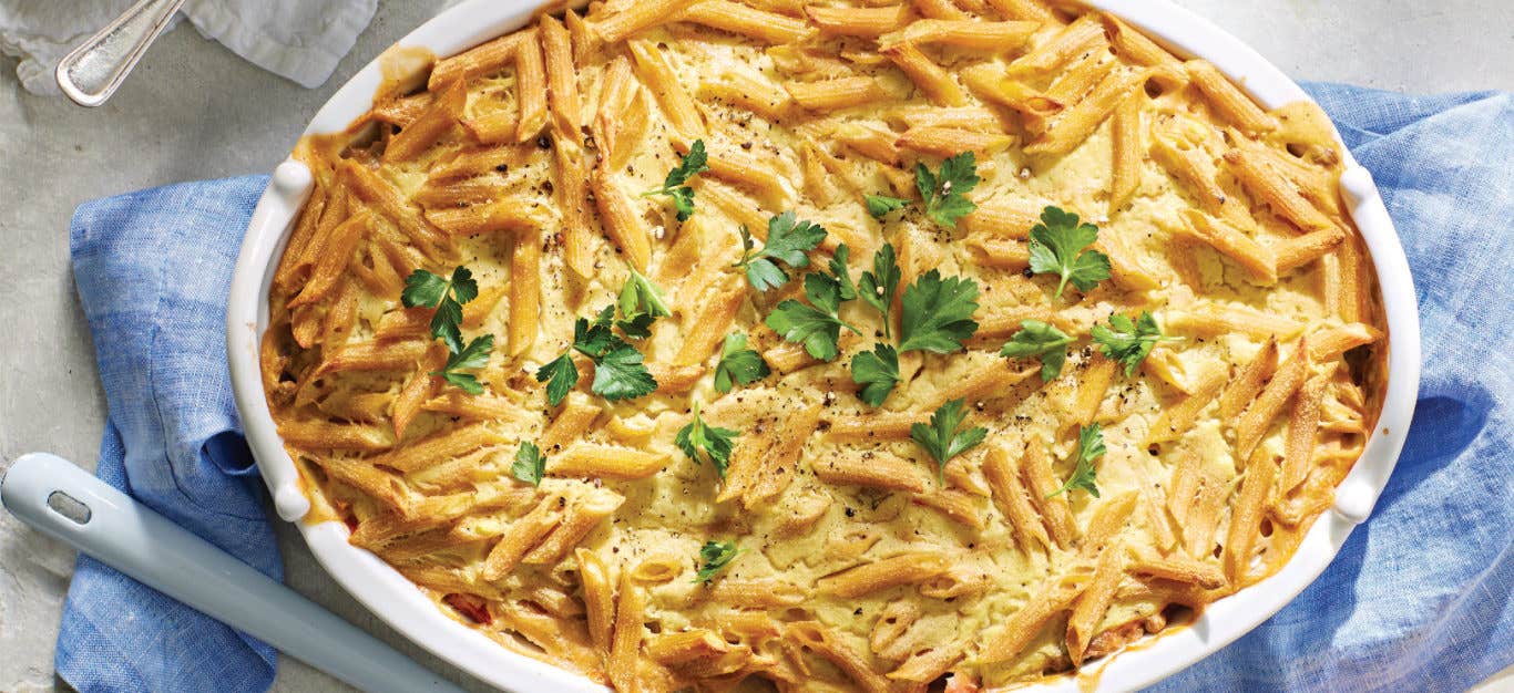 Vegan Pastitsio with Lentils (Greek Lasagna) in a white casserole dish garnished with flat leaf parsley