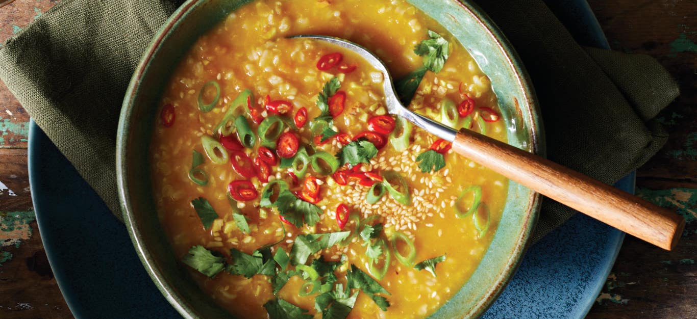 Silky Squash Vietnamese Rice Porridge in a green ceramic bowl with a wooden-handled spoon resting in the bowl