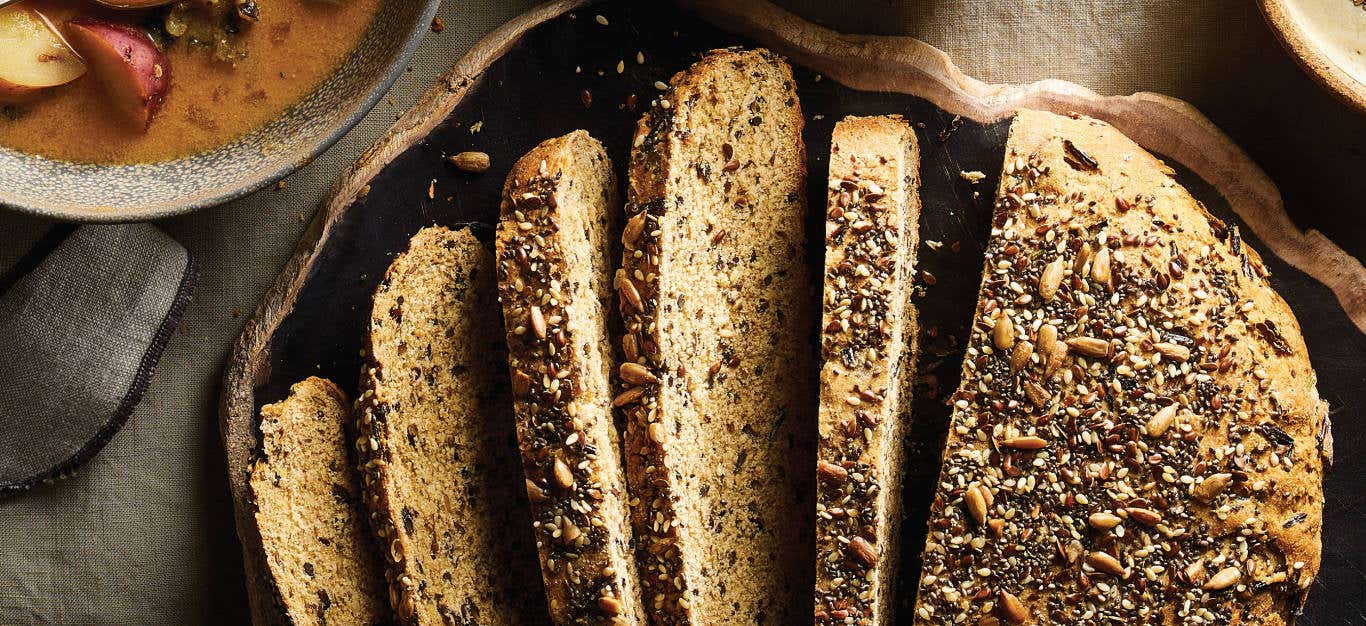 Seed Bread with Wild Rice and Herbs on a wooden platter cut into slices