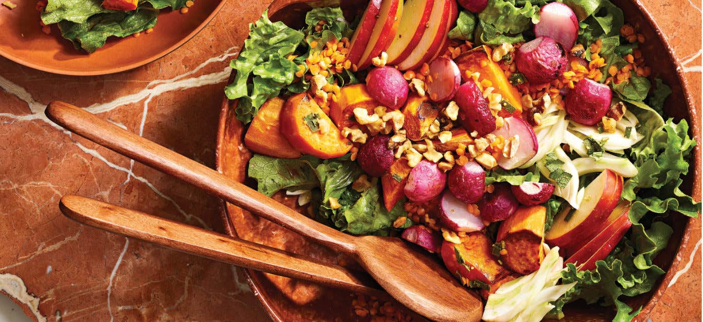 Roasted Radish Salad with Sweet Potato and Apple in a wooden serving bowl with wooden serving spoons resting in the bowl