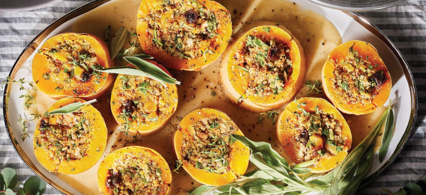 Quinoa-Stuffed Butternut Squash with Arugula, Pecans, and a Savory Gravy on a platter garnished with fresh sage leaves