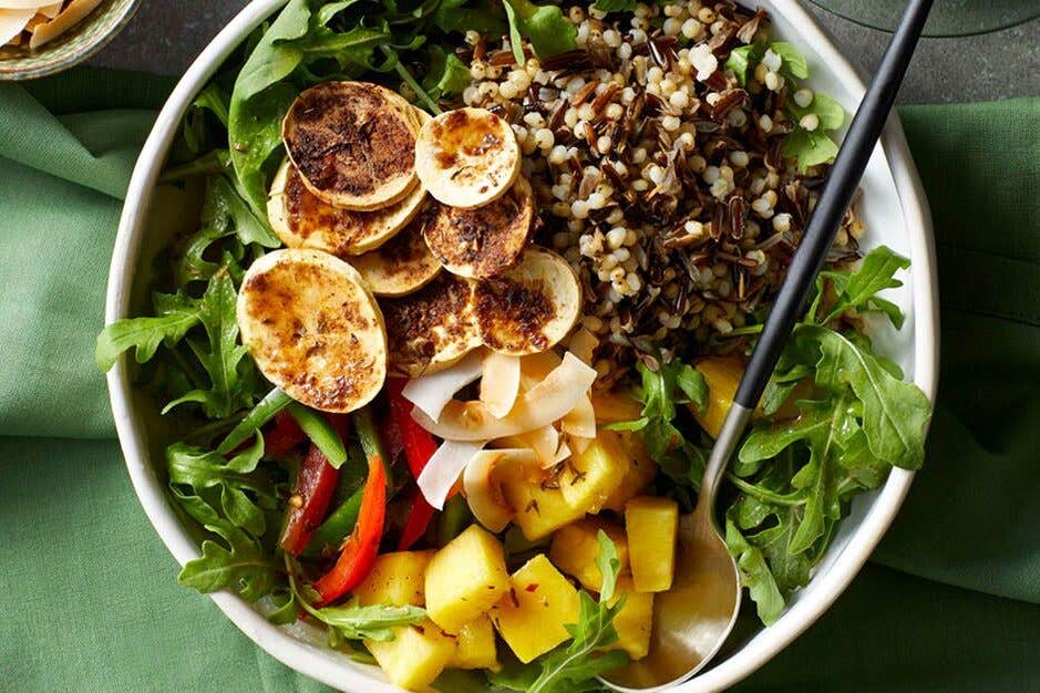 Colorful grain bowls with greens and sliced, crispy plantain chips, seasoned with jerk spices