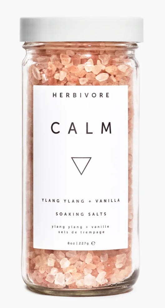 Herbivore brand Calm soaking salts, shown in a glass jar, with large pink salt crystals that include ylang ylang, vanilla sels de trempage