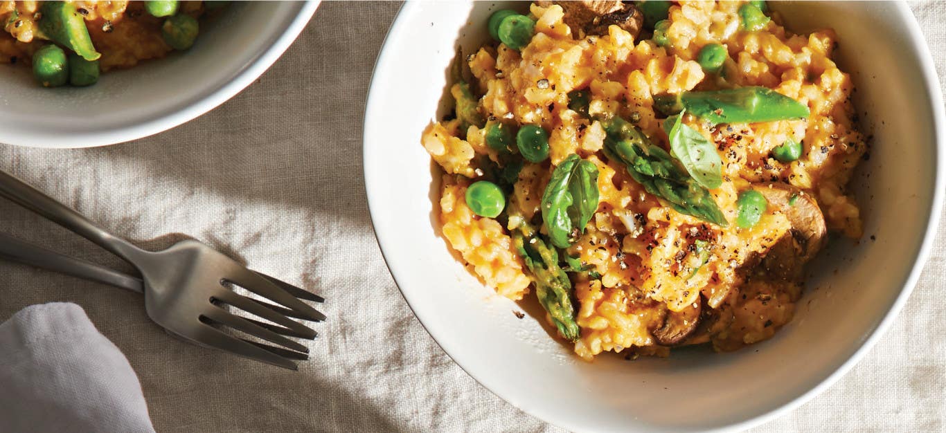 Easy Gluten-Free Risotto in a white serving bowl on a white tablecloth next to two forks