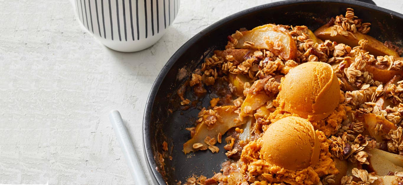 Maple-Ginger Spiced Pear Crisp with Oats in a cast-iron skillet on a marble countertop