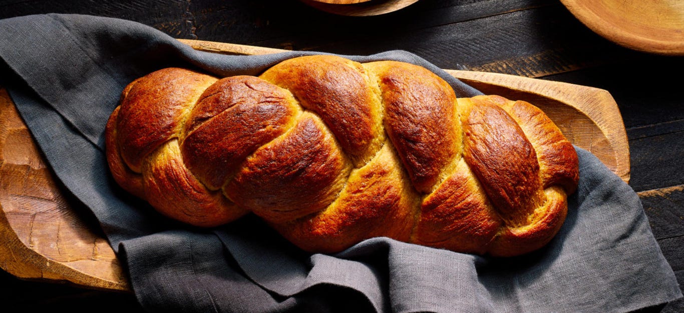 Vegan Challah Bread in a long wooden bowl on top of a blue linen towel