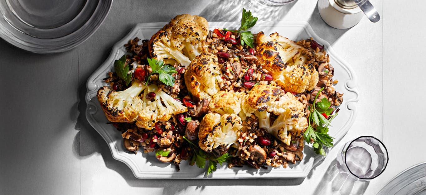 Whole Braised Cauliflower with Mixed-Grain Pilaf on a white serving platter