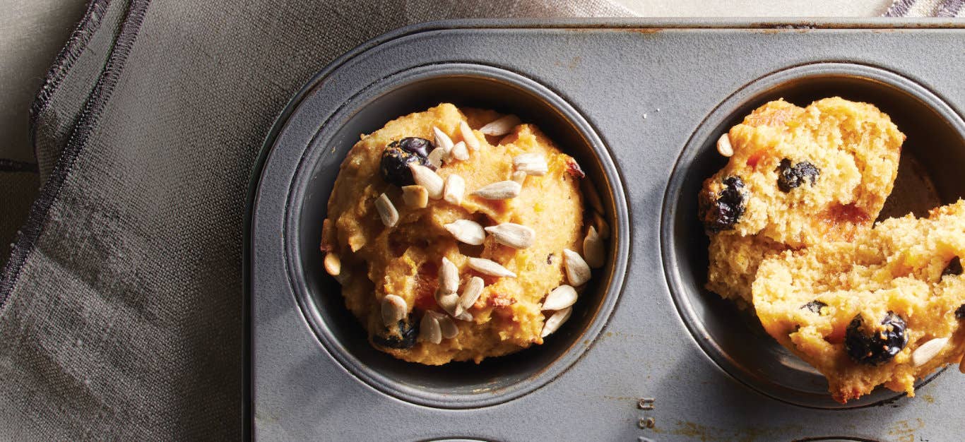 Two Vegan Cranberry Orange Muffins in a metal muffin pan