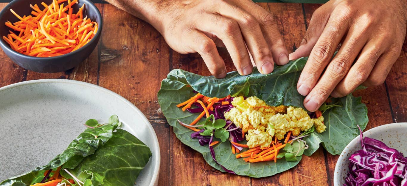 Close up of two hands rolling Dom Thompson's "Egg Salad” Collard Wraps on a wooden counter