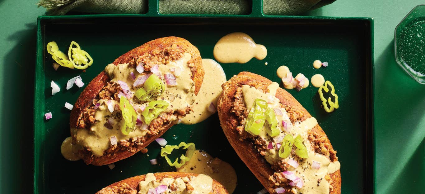 Three Vegan Italian Sausage Grinder Sandwiches topped with a cheesy vegan sauce