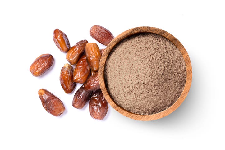 Pulverized dates (date sugar) in a bowl beside whole dates