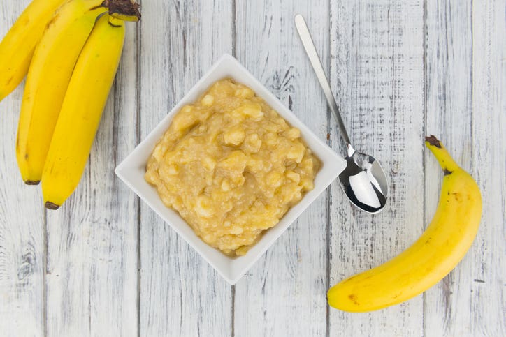 four whole bananas shown beside a bowl of mashed bananas for natural sweetening