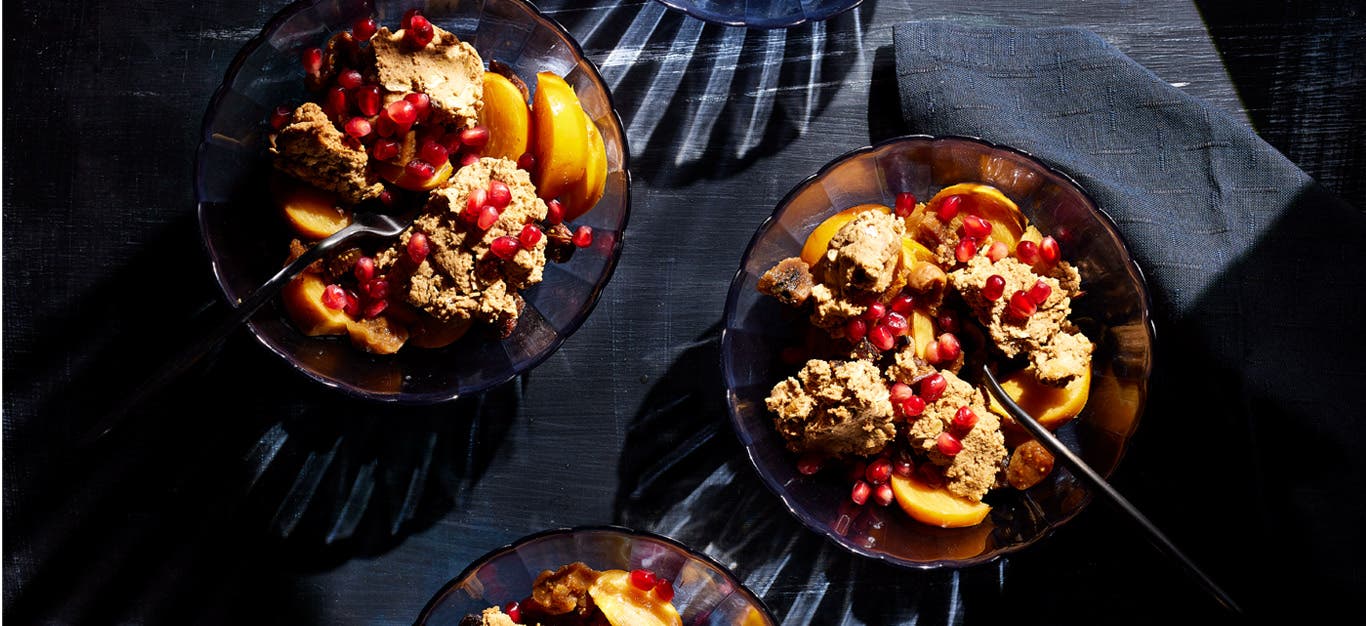 Two servings of Persimmon Fig Crisp with Golden Figs in glass bowls with pomegranate arils sprinkled on top