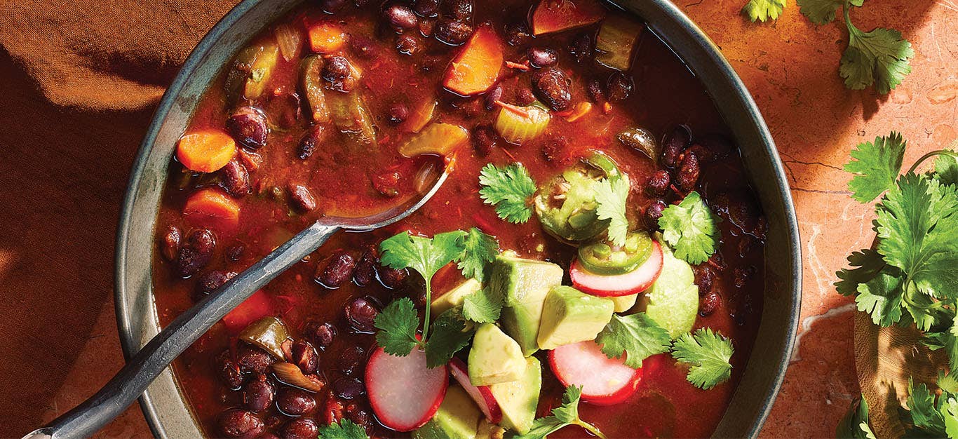 A bowl of Black Bean Chili garnished with quick-pickled avocado, radish, and jalapeño